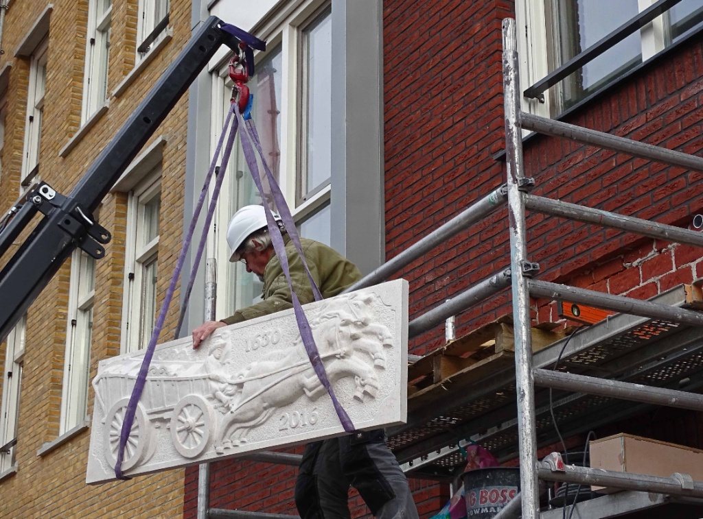 Gevelsteen die aan een monumentale gevel wordt geplaatst